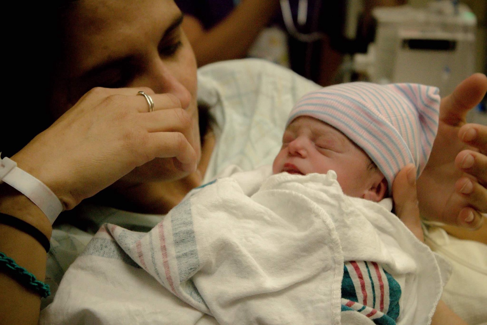 Two women smiling in a hospital bed with a newborn